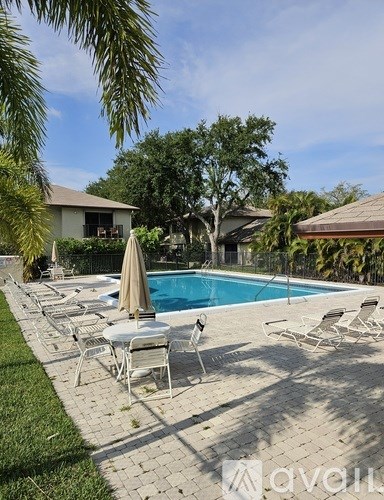 A pool surrounded by chairs and umbrellas with a house in the background.