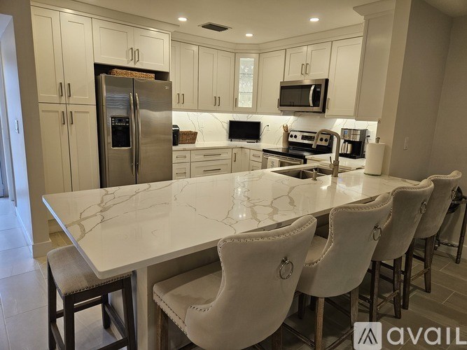 A kitchen with a marble table and white chairs.