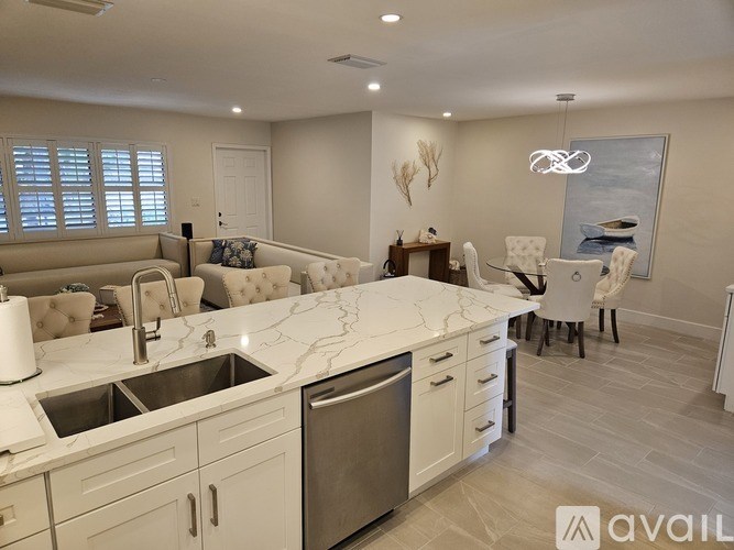 A modern kitchen with white cabinets and a marble countertop.