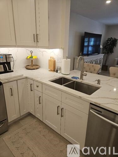 A kitchen with white cabinets and a marble countertop.