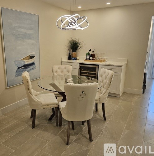 A modern dining room with a glass table and white chairs.