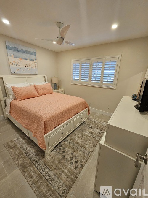 A bedroom with a bed, a ceiling fan, and a rug on the floor.