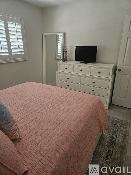 A bedroom with a bed, dresser, and television.