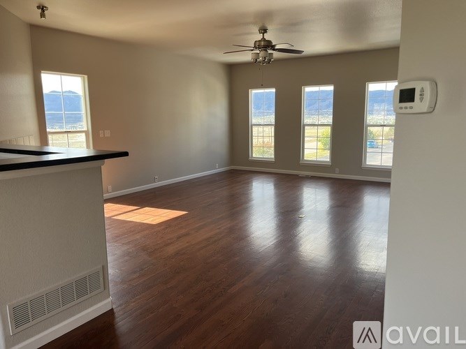 A spacious room with wooden floors and a ceiling fan.