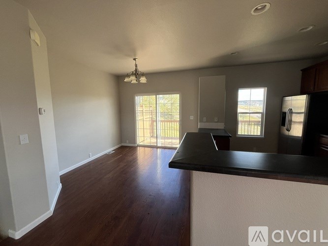 A large empty room with a bar counter and a balcony with a view of trees.