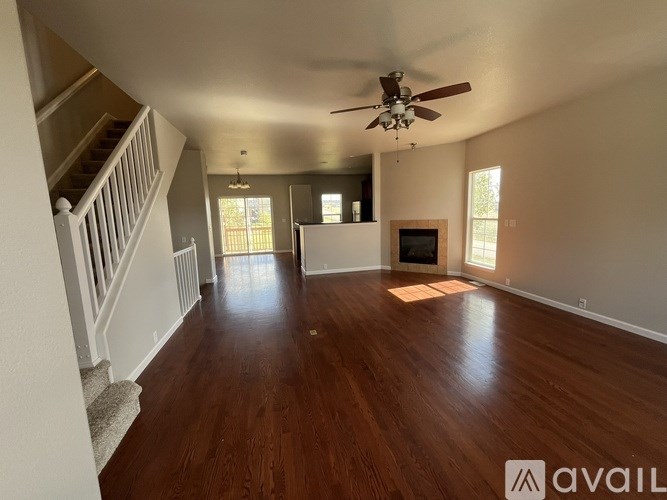 A spacious living room with wood flooring and a ceiling fan.