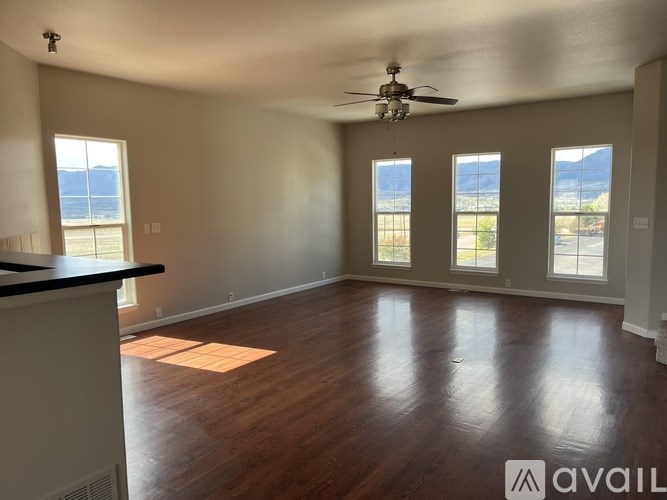 A spacious room with a ceiling fan and large windows.