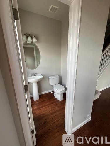 A white bathroom with a toilet, sink and mirror.
