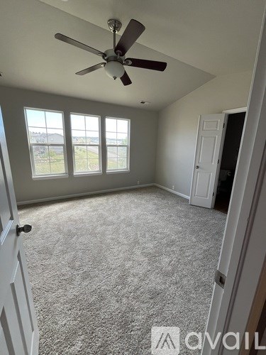 A room with a ceiling fan and carpeted floor.