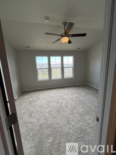 A room with a carpeted floor, a ceiling fan, and a window with blinds.