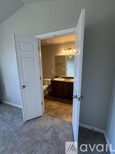 A white door is open to a bathroom with a toilet and sink.