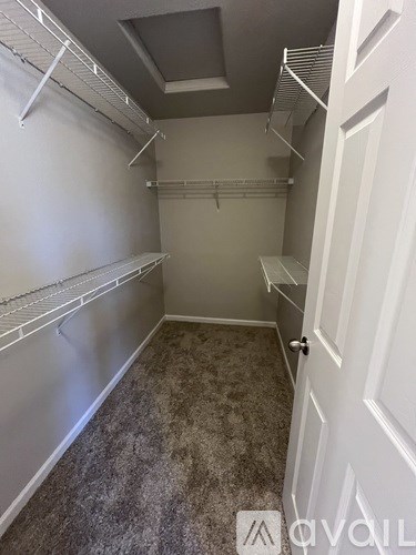 A walk-in closet with white shelves and a carpeted floor.