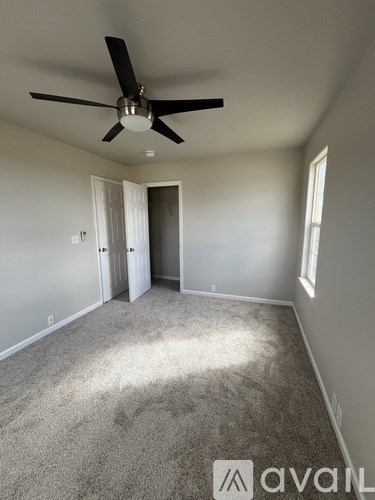 A room with a ceiling fan and carpeted floor.