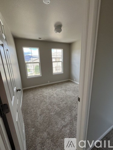 A room with a carpeted floor and two windows.