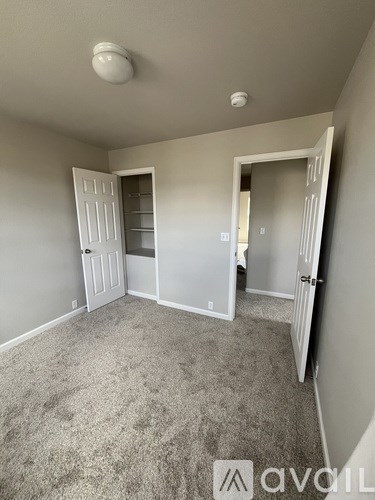 A room with a carpeted floor and two open doors.