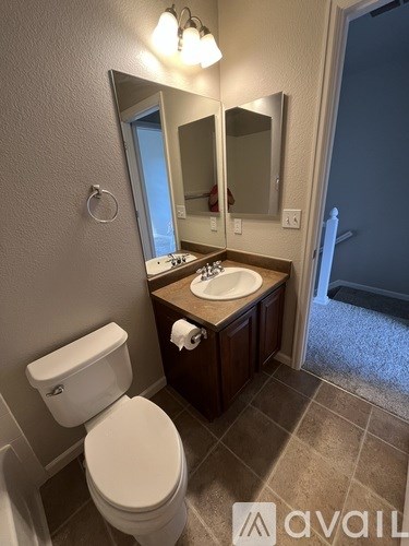 A bathroom with a toilet, sink, and mirror.
