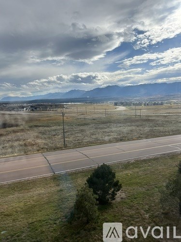 A road with a mountain range in the distance and a cloudy sky.
