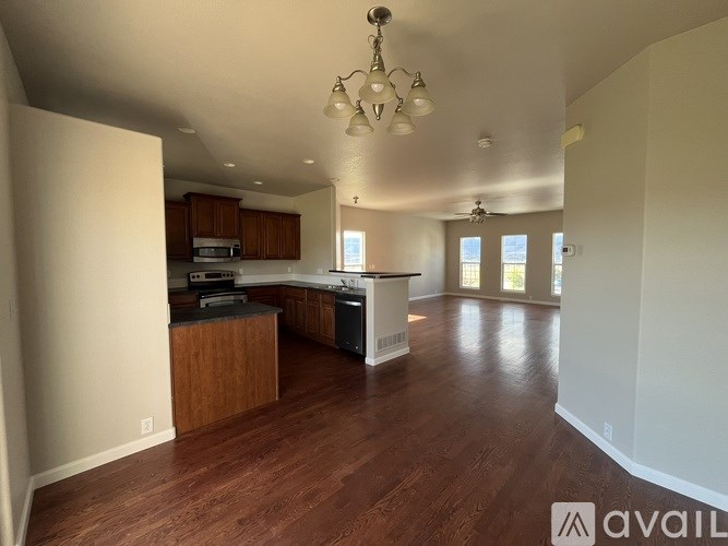 A spacious kitchen and living room with wooden floors and white walls.