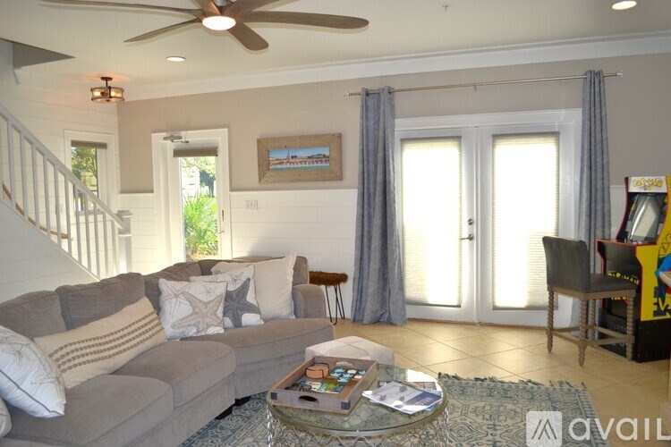 A living room with a grey couch, a coffee table, and a ceiling fan.