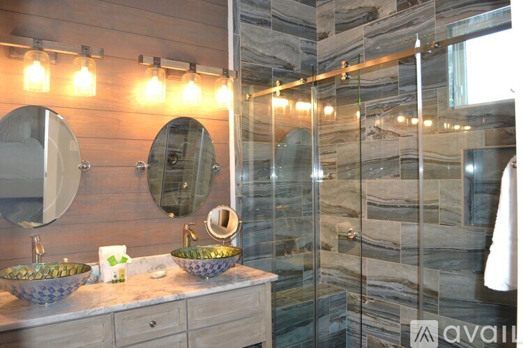 A bathroom with a marble wall and a glass shower stall.
