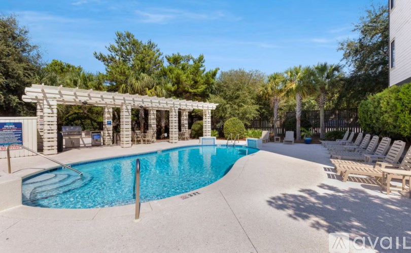 A pool area with sun loungers and a wooden pergola.