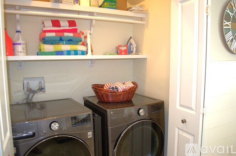 A laundry room with a basket of cloths on top of a washer.