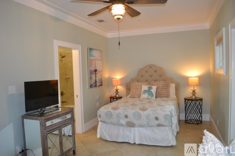 A bedroom with a bed, a television, and a ceiling fan.
