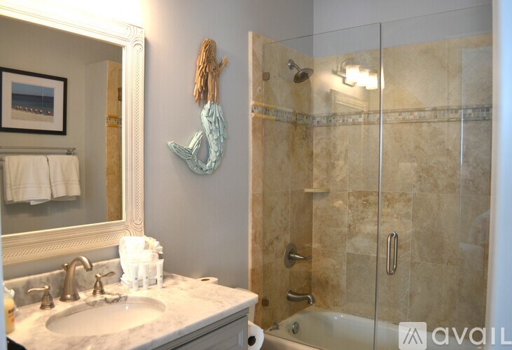 A bathroom with a marble countertop and a glass shower stall.