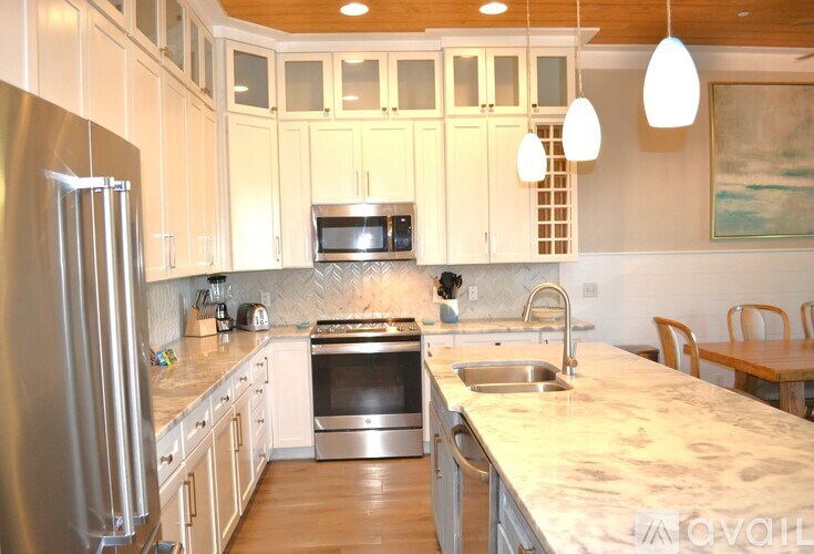 A kitchen with white cabinets and a stainless steel refrigerator.