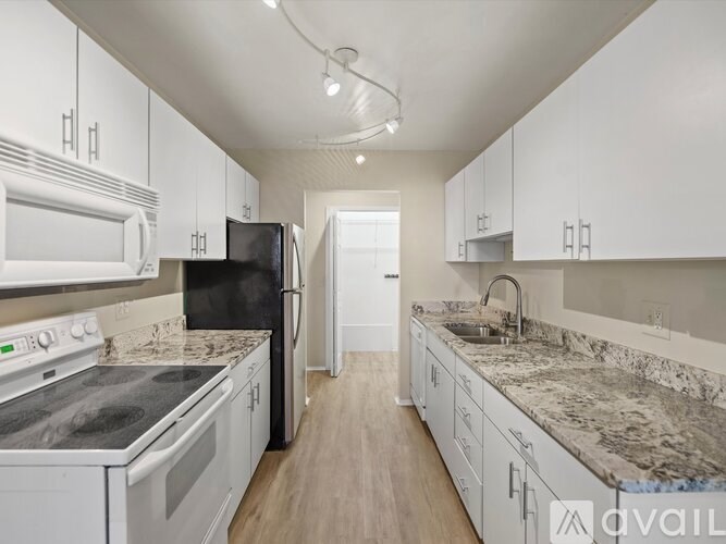 A kitchen with white cabinets and a black refrigerator.