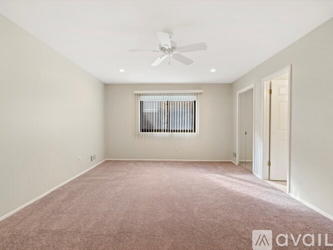 A room with a ceiling fan and carpeted floor.