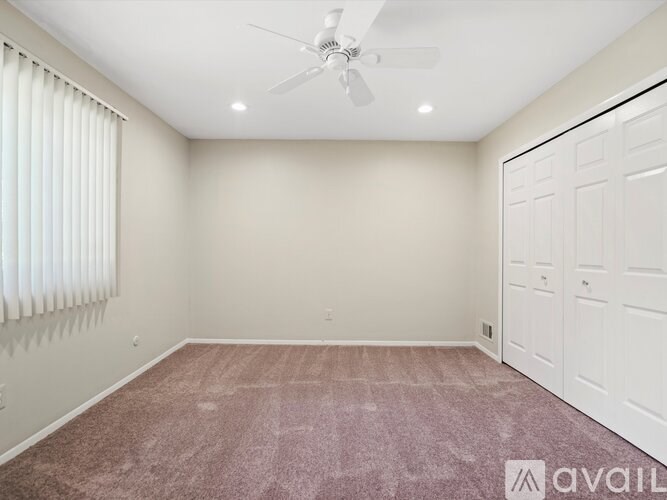 A room with a ceiling fan and a closed white door.