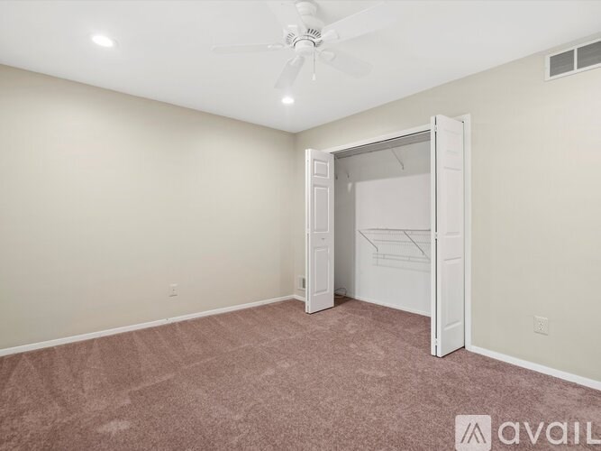 A room with a carpeted floor and a ceiling fan.