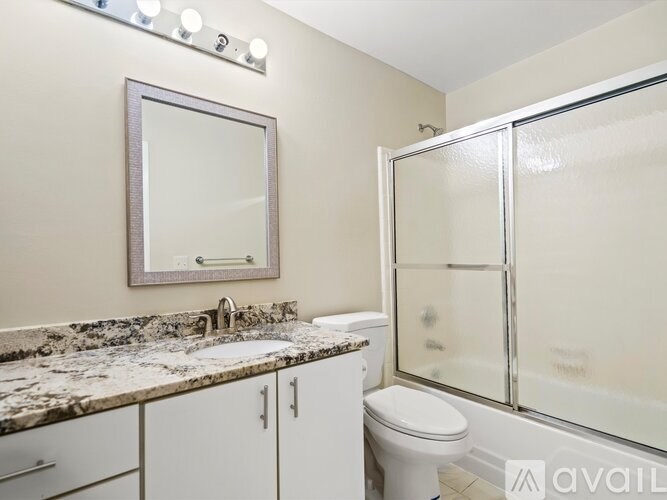 A bathroom with a marble countertop and a large mirror above it.