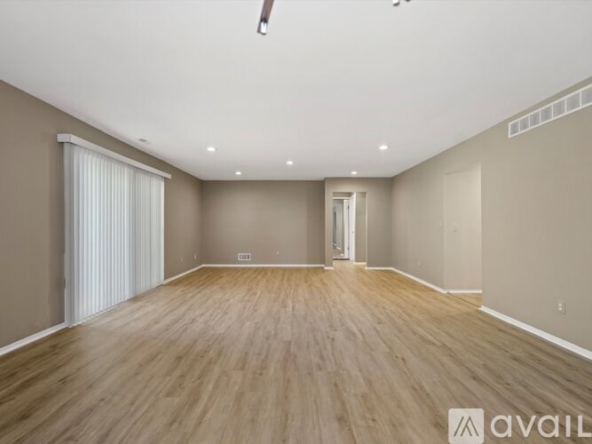 A spacious room with wooden flooring and a white ceiling.