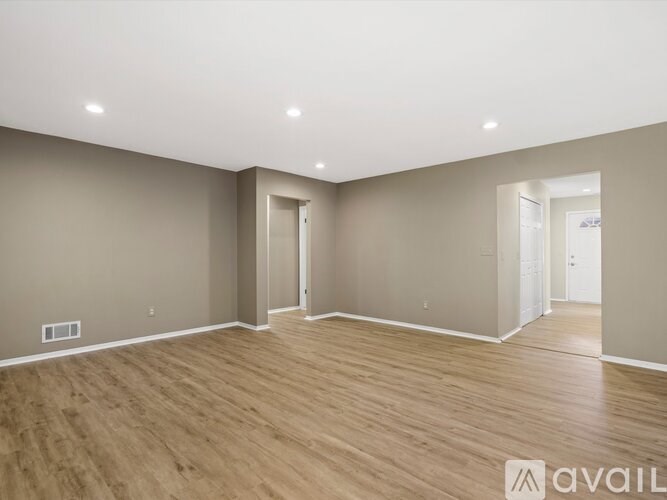 A spacious room with wooden flooring and beige walls.