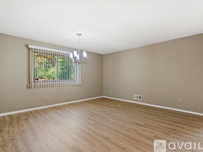 A room with wooden flooring and a window with blinds.