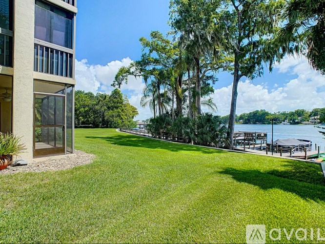 A modern house with a large lawn and trees in the background.