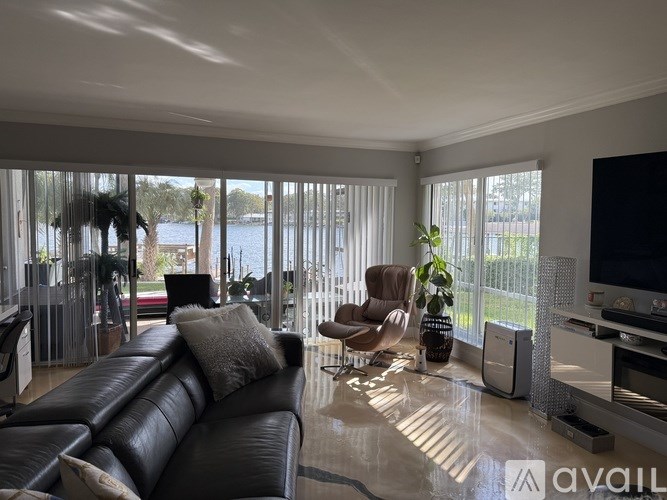 A living room with a black leather couch and a television.