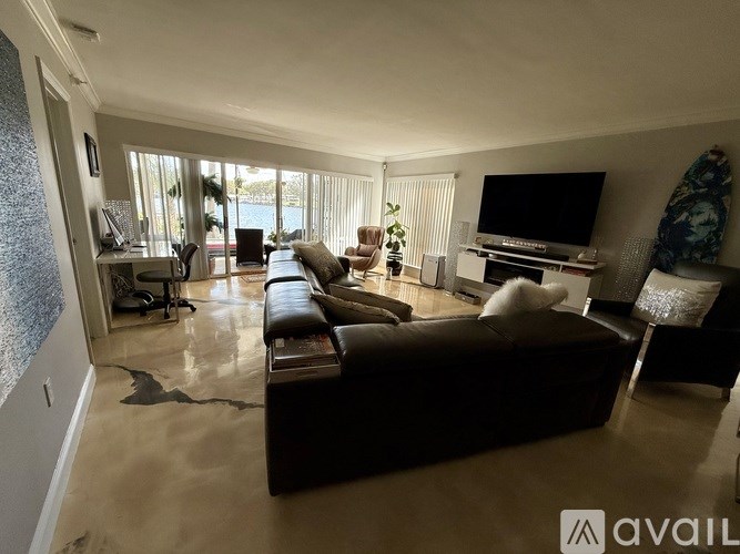 A living room with a brown leather couch and a television on a stand.