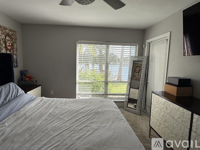 A bedroom with a large bed and a window with blinds.