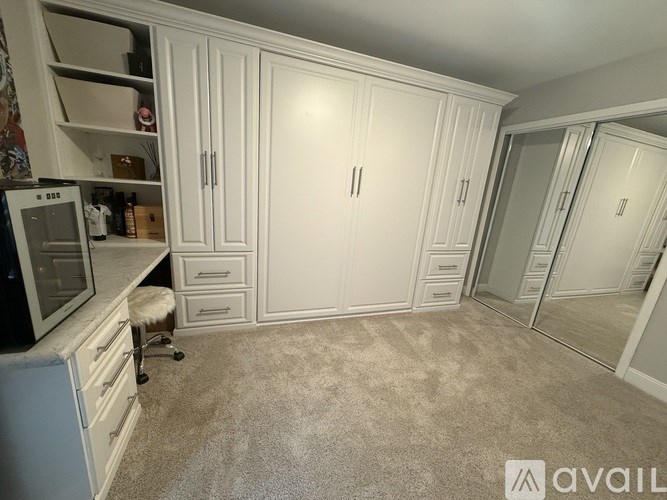 A kitchen with white cabinets and a carpeted floor.
