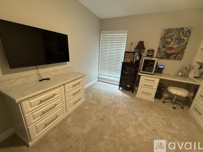 A room with a television, a desk with drawers, and a chair.