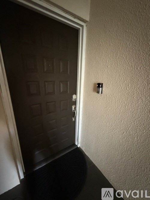 A black door with a silver handle and a wall mounted security system.