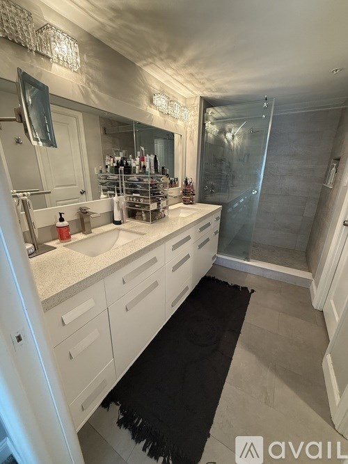 A bathroom with a sink, mirror, and shower.