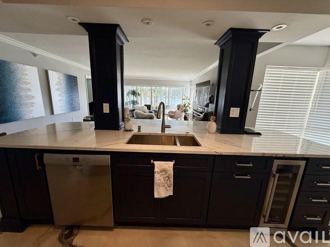 A kitchen with black cabinets and a stainless steel dishwasher.