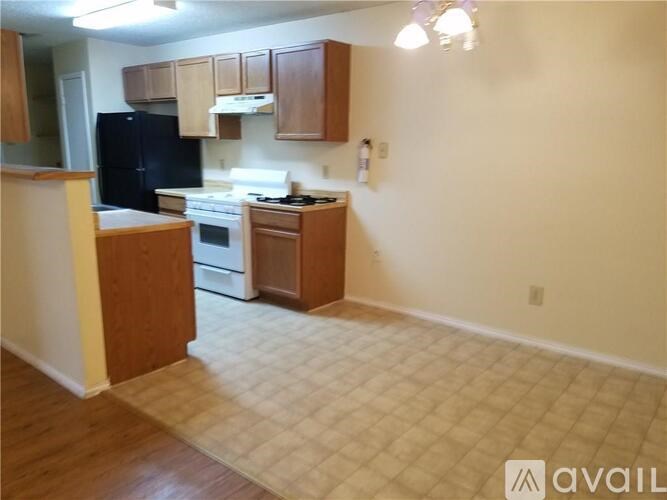 A kitchen with a black fridge, white stove, and wooden cabinets.