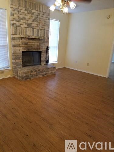 A room with a stone fireplace and wooden flooring.