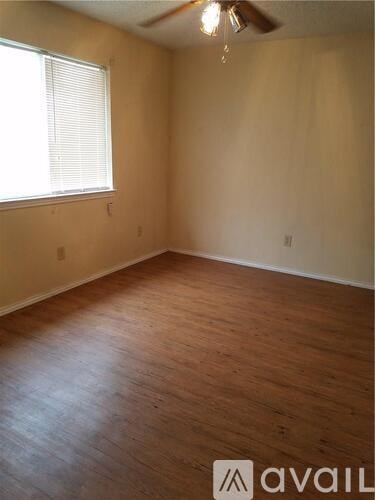 A room with wooden flooring and a window with blinds.