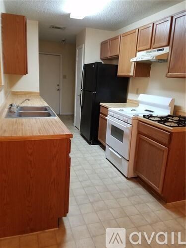 A kitchen with a black refrigerator and white appliances.